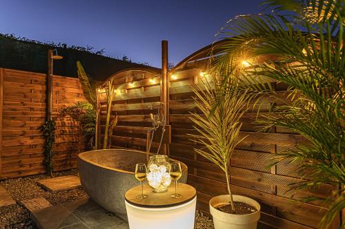 a bath tub sitting on a patio with glasses of wine at Magnifique Bungalow et Jacuzzi au cœur des plages in Le Moule