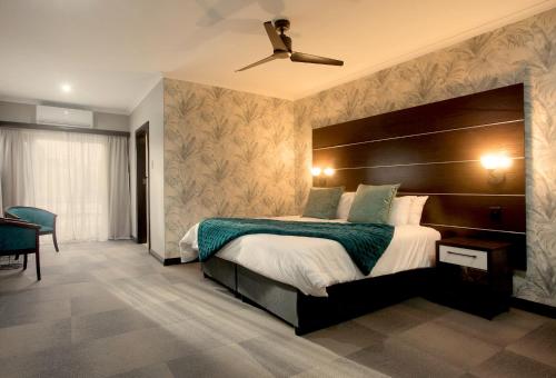 The Hub Boutique Hotel في بورت اليزابيث: غرفة نوم بسرير كبير ومروحة سقف
