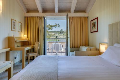 a hotel room with a bed and a desk and a balcony at Hotel Caesius Thermae & Spa Resort in Bardolino