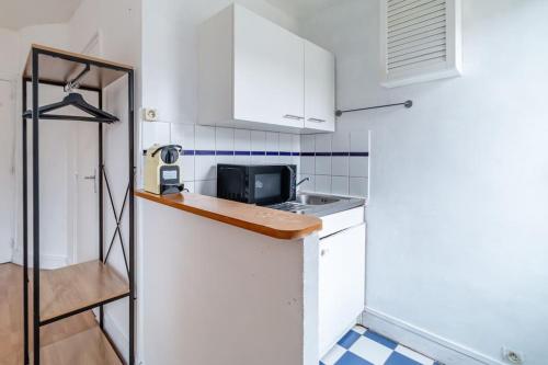 une petite cuisine avec un évier et un micro-ondes dans l'établissement Studio Proche Nation - Paris, à Paris
