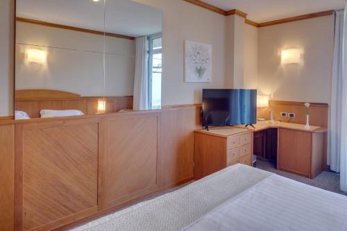 a bedroom with a bed and a desk with a television at Hotel Caesius Thermae & Spa Resort in Bardolino