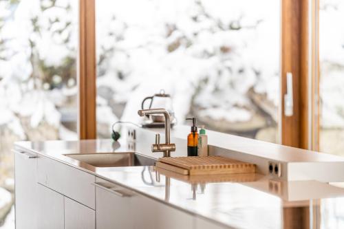 a white kitchen with a sink and a window at Above the Clouds - spacious chalet with great view in Plan Fey