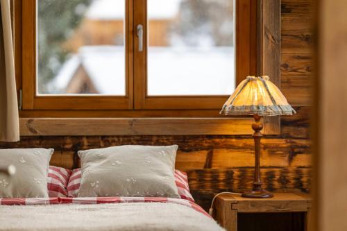 a bedroom with a bed with a window and a lamp at Above the Clouds - spacious chalet with great view in Plan Fey