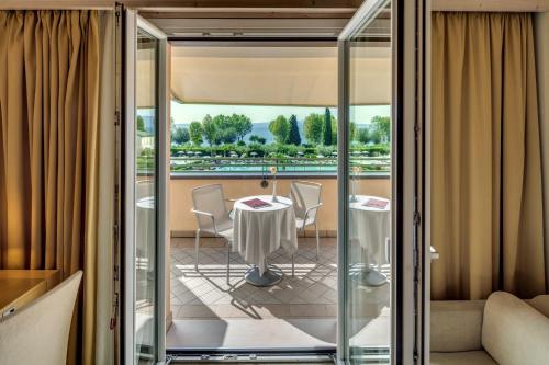 a room with a table and chairs on a balcony at Hotel Caesius Thermae & Spa Resort in Bardolino