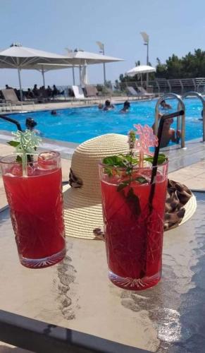 two cocktails sitting on a table near a swimming pool at Giannis Village Resort in Astakós