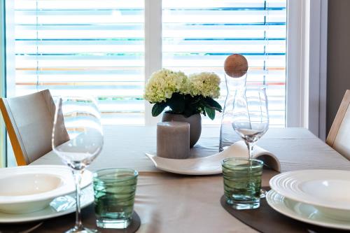 a dining room table with glasses and a vase of flowers at Residence Engel in Nova Levante