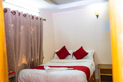 a bedroom with a bed with red and white pillows at Naya Gaun Eco Resort in Pokhara