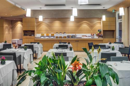 a dining room with white tables and plants at Hotel Caesius Thermae & Spa Resort in Bardolino