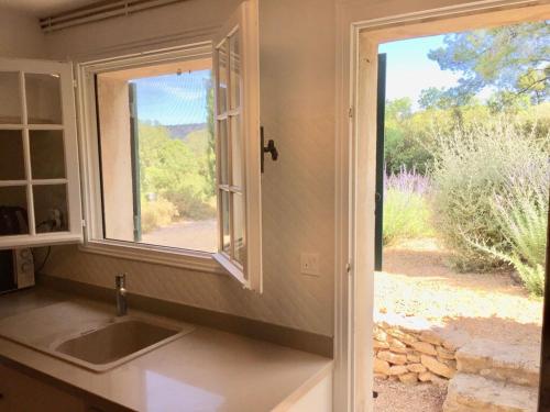 une cuisine avec un évier et une fenêtre dans l'établissement Mas provençal dans les Alpilles, aux Baux-de-Provence