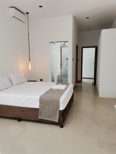 a white bedroom with a large bed and a glass door at Dzixile in Gueima