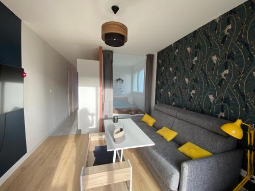 sala de estar con sofá gris y almohadas amarillas en Appartement BIENVENUE au calme quartier Venoix en Caen