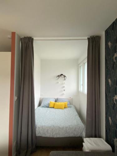 a bedroom with a bed with yellow pillows at Appartement BIENVENUE in Caen