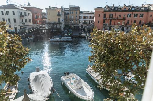 two boats are docked in a canal with buildings at Pavillon Suite in Peschiera del Garda