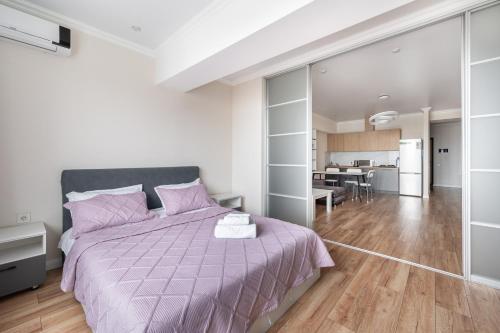 a bedroom with a purple bed and a kitchen at One Bedroom Apartment Near Arbat In The Center of Almaty in Almaty