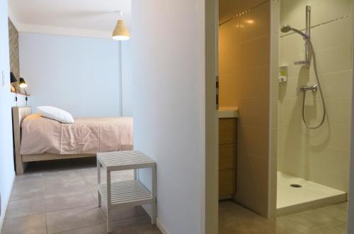 LaudunにあるMaison d'hôtes La Bignoneのバスルーム(シャワー付)、ベッド1台、スツールが備わります。