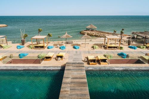 una piscina con sedie e ombrelloni accanto all'oceano di Bavaro Beach Dakhla a Dakhla