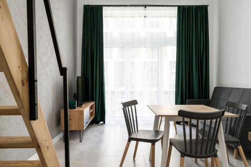 a dining room with green curtains and a table and chairs at RentPlanet - Apartamenty Zarembowicza in Wrocław