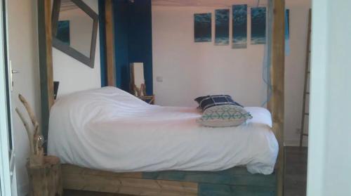 um quarto com uma cama com lençóis brancos e um espelho em Maison vue mer avec piscine em Plouider