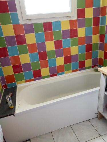 y baño con paredes de azulejos de colores y bañera. en Perle du Littoral Nord en Boulogne-sur-Mer