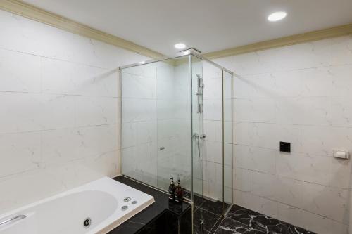 a bathroom with a shower and a tub at Pale De Cz Condo in Busan