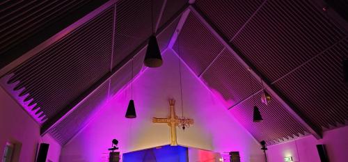 a church with a cross and purple lights at Gamvik brakkebo as in Gamvik