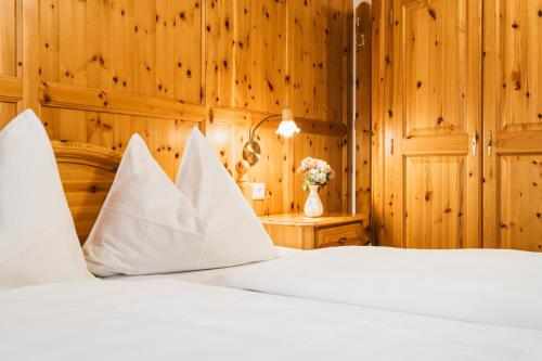 a bed with white sheets and a vase with flowers at Hörandlhof in Aigen im Ennstal