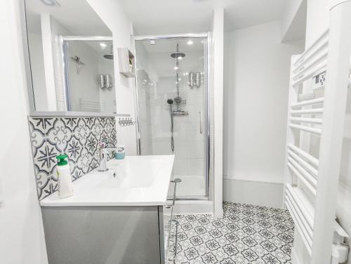 La salle de bains blanche est pourvue d'un lavabo et d'une douche. dans l'établissement Le Saint Vincent - 4/6P - 300m de la plage, au Havre