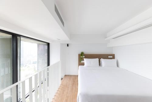 a white bedroom with a bed and a window at Lloyd's Inn Kuala Lumpur in Kuala Lumpur