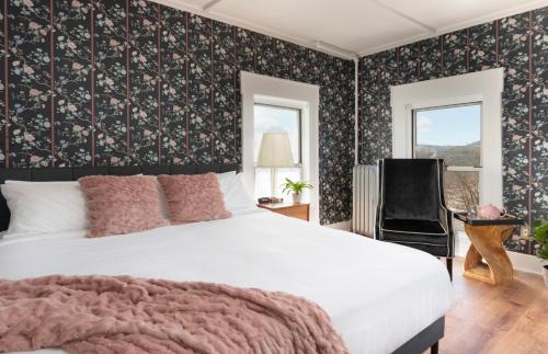 a bedroom with a white bed and a chair at Thayers Inn in Littleton