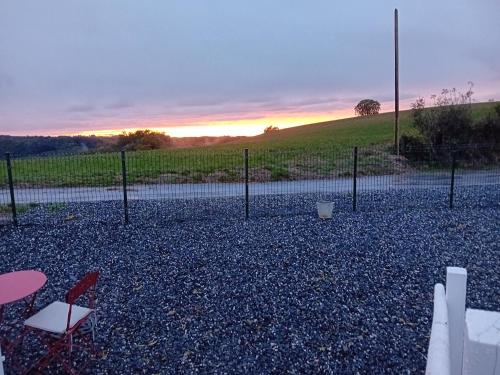 a fence with chairs and a sunset in the background at ROUPILLON A JANET in Curvalle