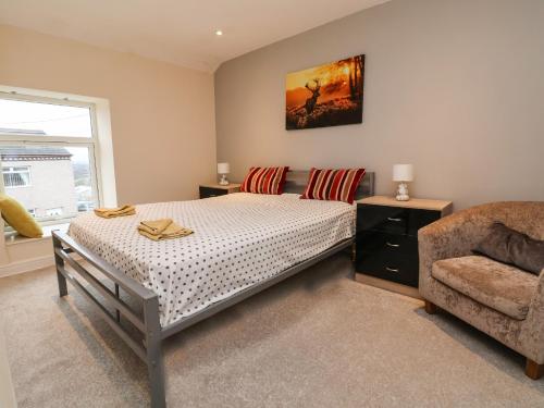 a bedroom with a bed and a chair at 2 Stoneleigh Cottage in Wrexham