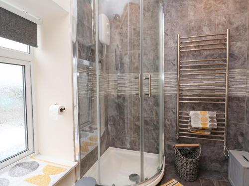 a shower with a glass door in a bathroom at 2 Stoneleigh Cottage in Wrexham