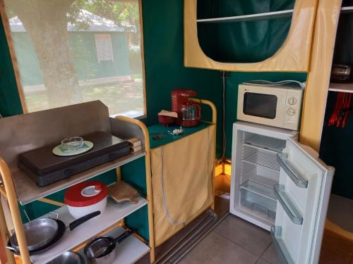 a small kitchen with a stove and a microwave at Camping de Rouergue in Villefranche-de-Rouergue