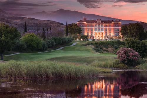 ein Herrenhaus auf einem Golfplatz mit einem See davor in der Unterkunft Anantara Villa Padierna Palace Benahavís Marbella Resort - A Leading Hotel of the World in Estepona