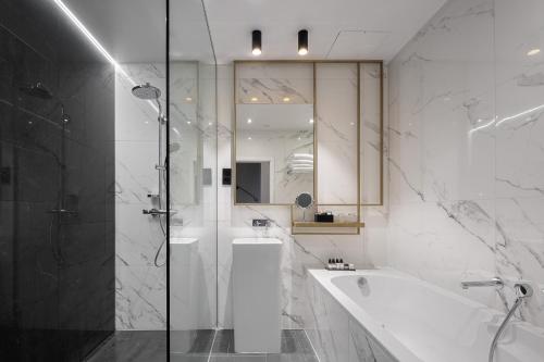 a white bathroom with a tub and a shower at Century Old Town Prague - MGallery Collection in Prague