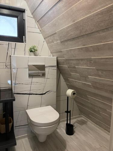 a bathroom with a toilet and a wooden wall at Valea Mosului - Cozy A Frame in Petroşani