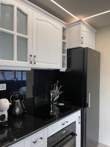 a kitchen with white cabinets and a black refrigerator at Valea Mosului - Cozy A Frame in Petroşani
