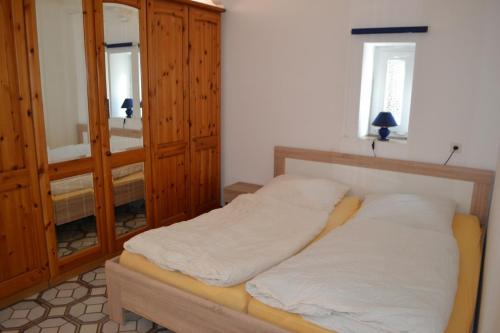 a bedroom with a bed with white sheets and a mirror at Immensee App A in Ehst