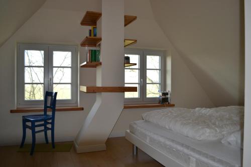 a bedroom with a bed and a chair and windows at Friesenhus in Katingsiel