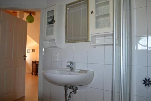 a white bathroom with a sink and a mirror at Friesenhus in Katingsiel