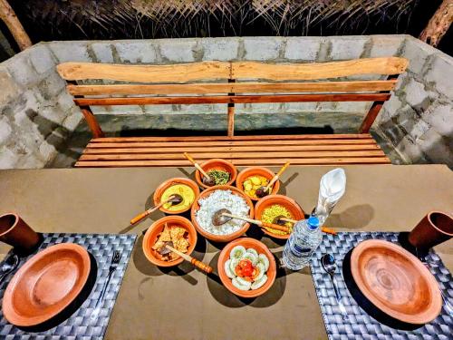 a table with bowls of food and a bench at Maika safari lodge in Udawalawe