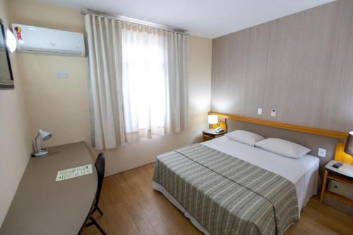 a hotel room with a bed and a window at Sables Hotel Guarulhos in Guarulhos