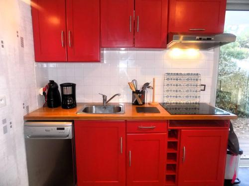 een keuken met rode kasten en een wastafel bij Saint Georges de Didonne - APPARTEMENT en rez-de-chaussée - proche PLAGE in Saint-Georges-de-Didonne