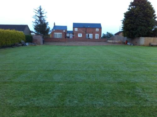 a large grassy yard with a house in the background at Immaculate historical 2-Bed Cottage in The Fens in Lutton