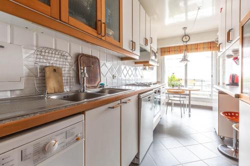 une cuisine avec des armoires blanches et un évier dans l'établissement Veeve - The Salon in the Sky, à Paris