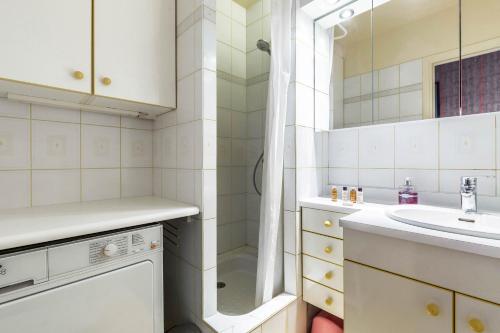 une salle de bain blanche avec un lavabo et une douche dans l'établissement Veeve - The Salon in the Sky, à Paris