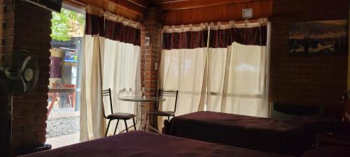 a bedroom with a bed and a window with a table and chairs at Posada Rivera in San Salvador de Jujuy