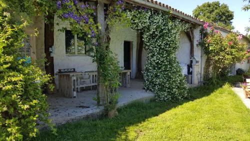 an ivy covered building with a table and flowers at Clos de la source Gironde in Saint-Martin-du-Bois