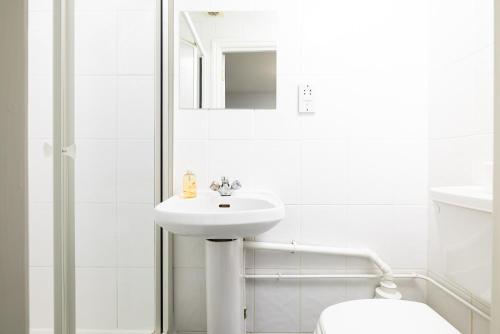 a white bathroom with a sink and a toilet at Charmstay Swiss Cottage in London