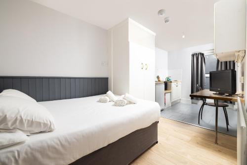 a bedroom with a bed and a desk with a television at Charmstay Swiss Cottage in London
